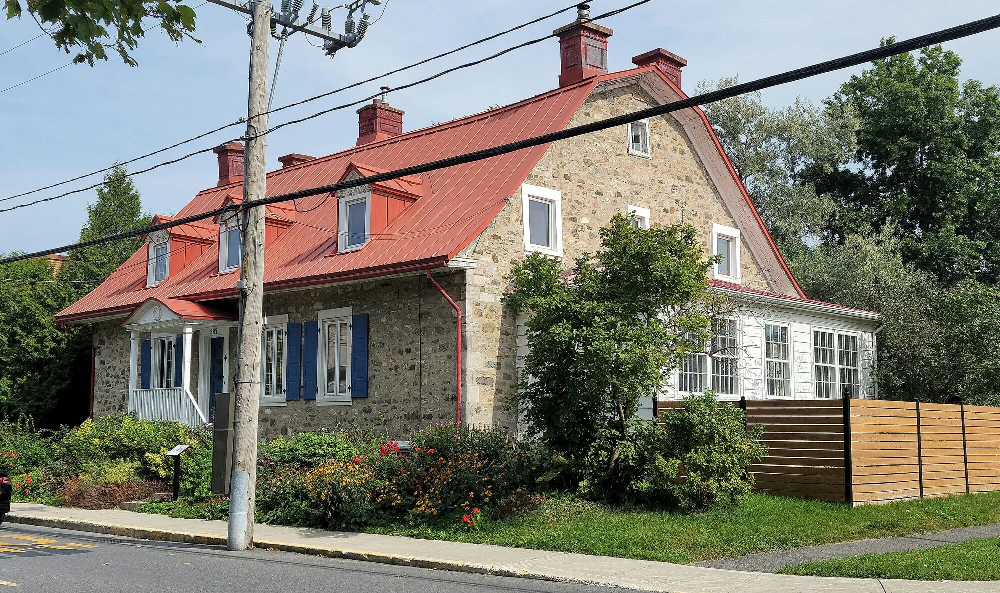 Maison patrimoniale en pierre au toit rouge, rue Sainte-Anne à Varennes